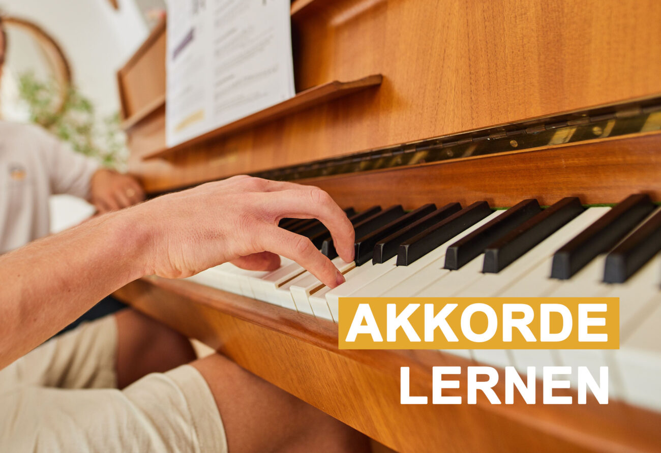Hand spielt Klaviertasten mit Text-Overlay 'AKKORDE LERNEN' - Klavierunterricht zu Hause